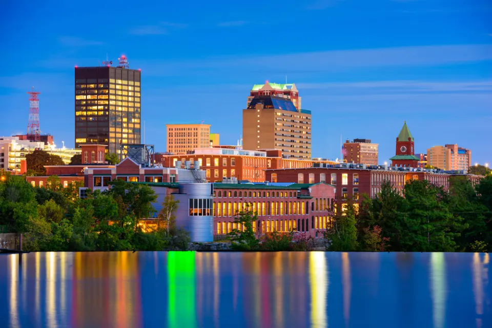 The downtown of Mancheste, New Hampshire is nestled against the Merrimack River in the final light of day.